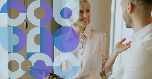 Photo of a smiling woman holding an iPad and chatting to a man. 