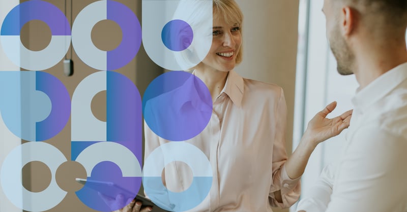 Photo of a smiling woman holding an iPad and chatting to a man. 