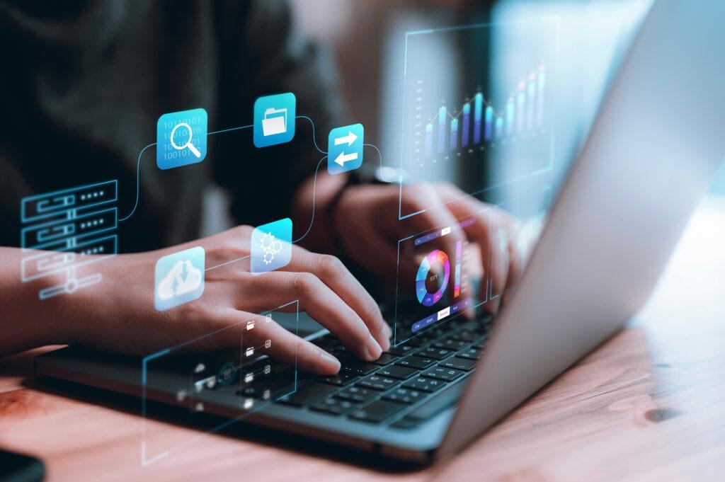 A close-up of hands typing on a laptop with floating graphics indicating technology