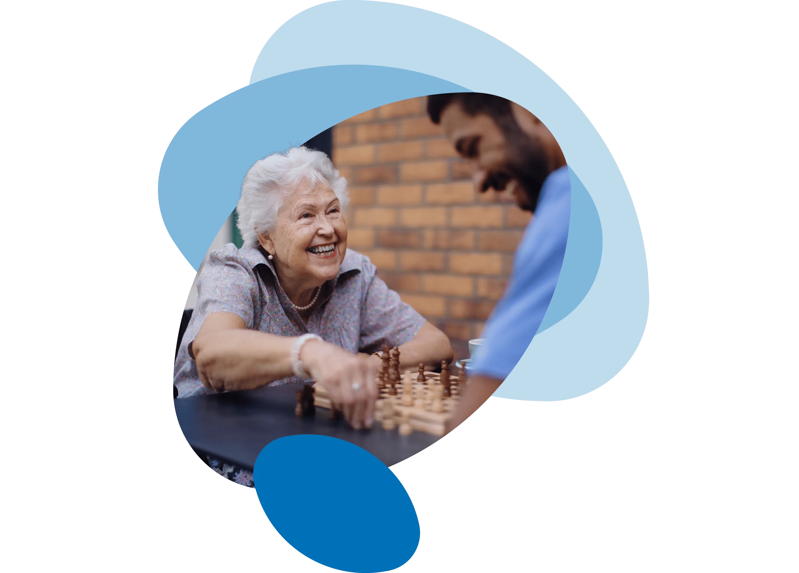 A smiling senior woman playing chess with a bearded male carer